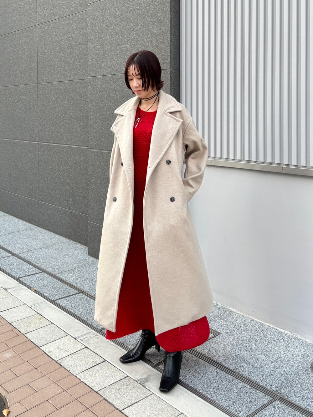 レッド系のワンピース、ホワイト系のチェスターコートを着用したレディースの冬コーディネートの2枚目の写真