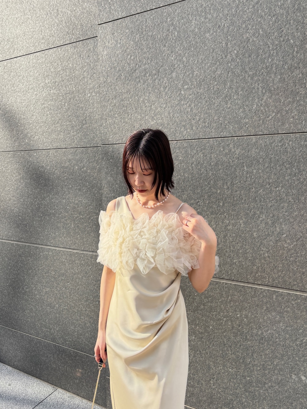 イエロー系のドレス、ブラック系のハンドバッグ、ブラック系のパンプスを着用したレディースの冬コーディネートの5枚目の写真