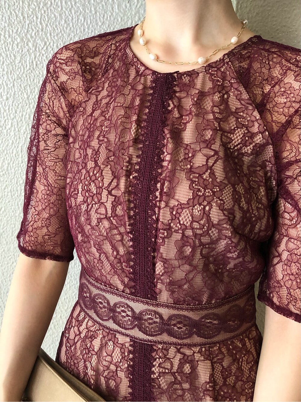 レッド系のドレス、ベージュ系のパンプス、ベージュ系のクラッチバッグを着用したレディースの秋コーディネートの6枚目の写真