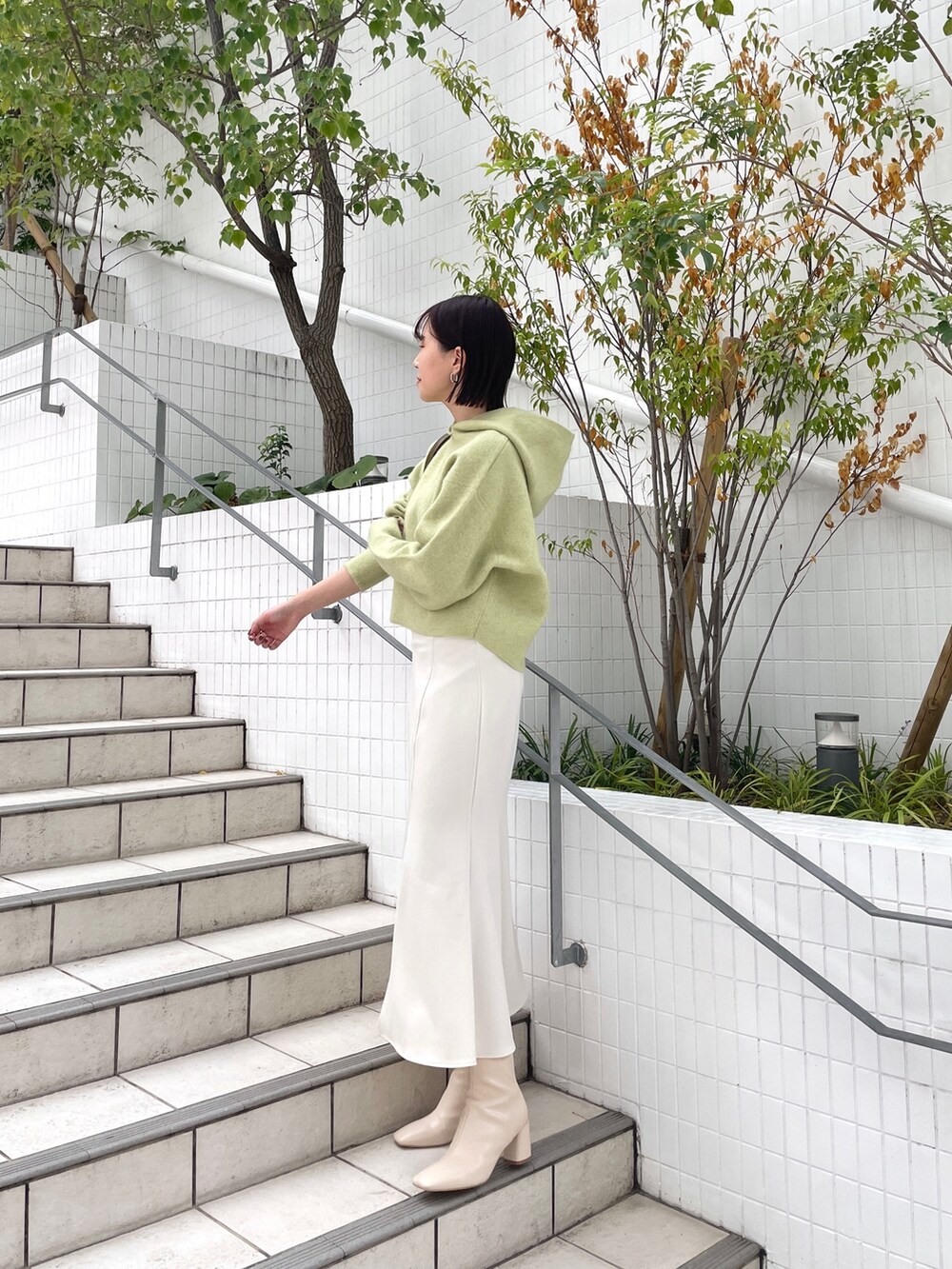 ホワイト系のスカート、グリーン系のパーカー、ホワイト系のブーツを着用したレディースの秋コーディネートの3枚目の写真