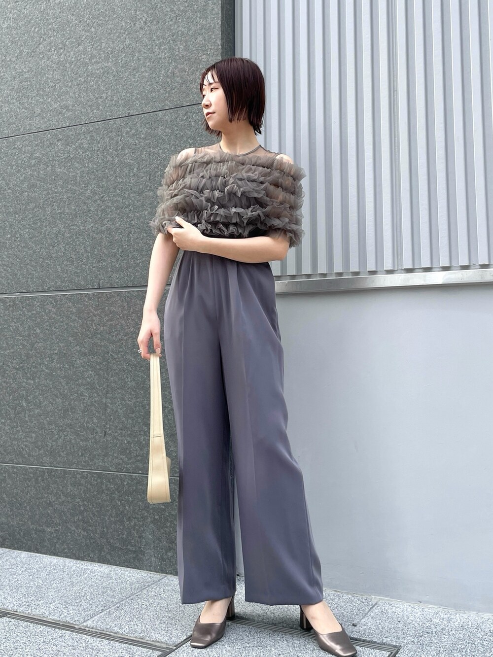 グレー系のパンツドレス、その他のパンプス、ベージュ系のテーラードジャケットを着用したレディースの春コーディネートの9枚目の写真