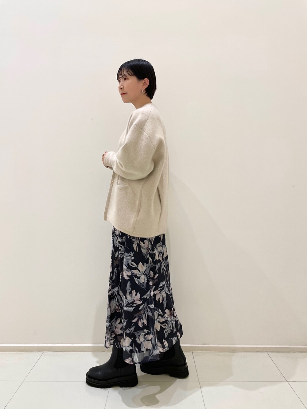 ホワイト系のカーディガン/ボレロ、ブルー系のワンピース、ブラック系のブーツを着用したレディースの冬コーディネートの5枚目の写真