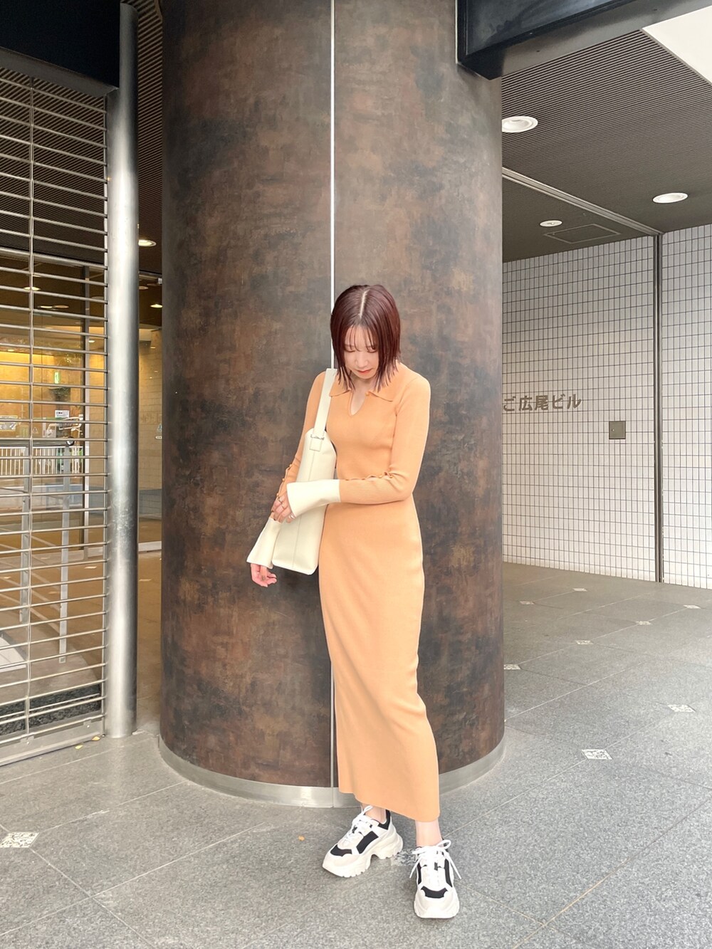 オレンジ系のワンピース、ホワイト系のショルダーバッグ、ブラック系のスニーカーを着用したレディースの冬コーディネートの3枚目の写真