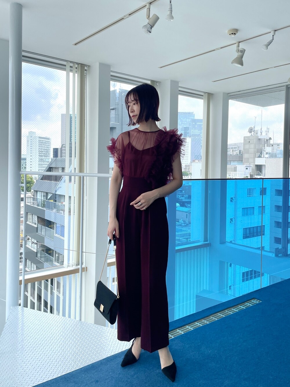 レッド系のパンツドレスを着用したレディースの春コーディネートの2枚目の写真