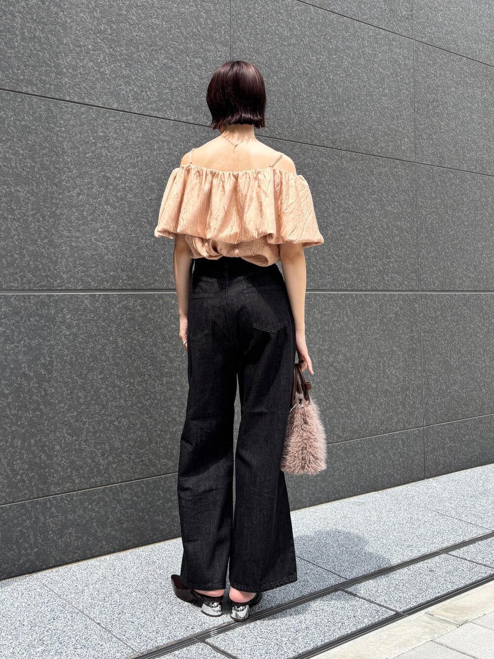 ブラック系のデニムパンツ、ブラウン系のパンプス、ブラウン系のボストンバッグを着用したレディースの夏コーディネートの2枚目の写真