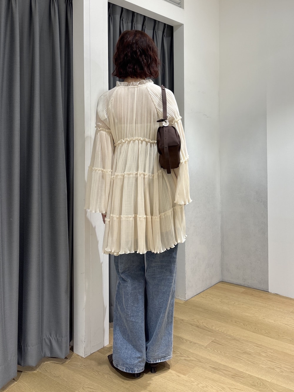 ホワイト系のワンピース、ブルー系のデニムパンツ、ブラウン系のハンドバッグを着用したレディースの秋コーディネートの4枚目の写真