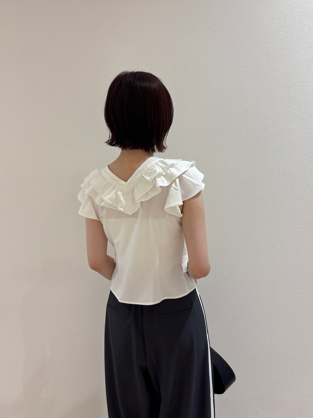ホワイト系のシャツ/ブラウス、ブラック系のハンドバッグ、ブラック系のパンプスを着用したレディースの夏コーディネートの5枚目の写真