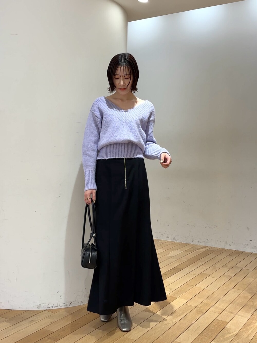 ブラック系のスカート、パープル系のニット/セーター、ホワイト系のダウンジャケット/コートを着用したレディースの冬コーディネートの7枚目の写真