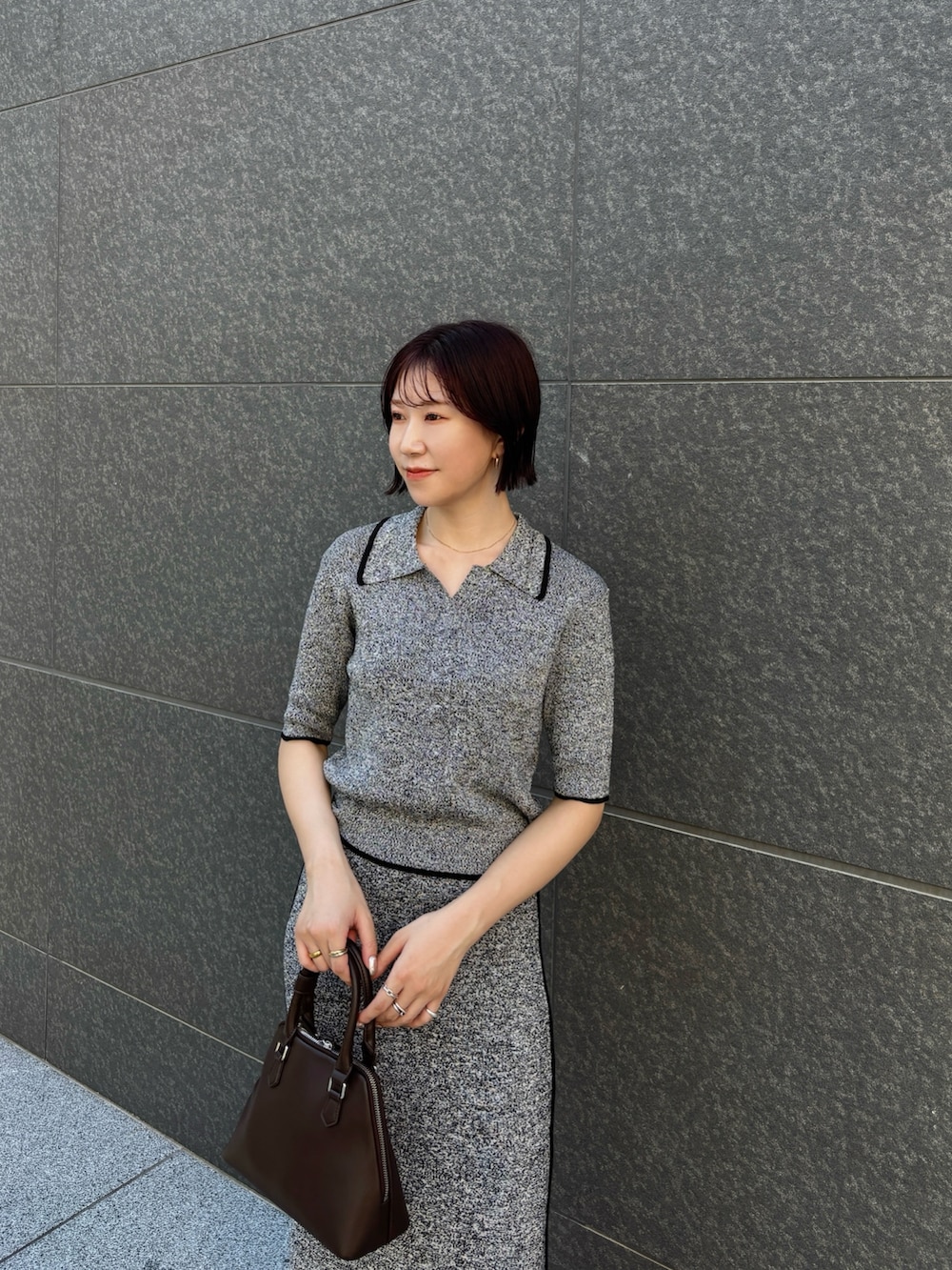 ブラック系のワンピース、ブラウン系のボストンバッグ、ブラウン系のパンプスを着用したレディースの夏コーディネートの4枚目の写真