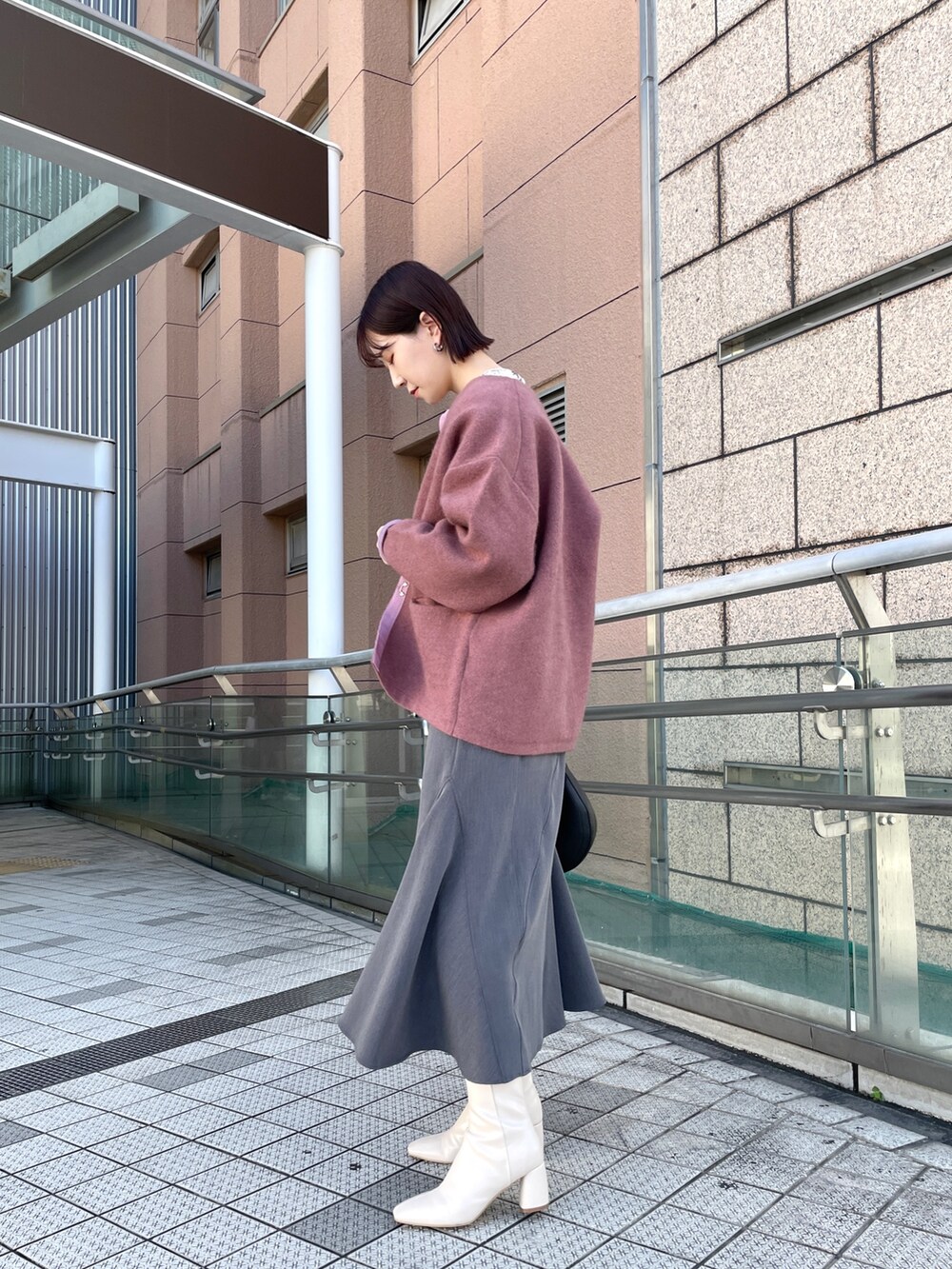 ピンク系のカーディガン/ボレロ、グレー系のスカート、ホワイト系のシャツ/ブラウスを着用したレディースの秋コーディネートの3枚目の写真