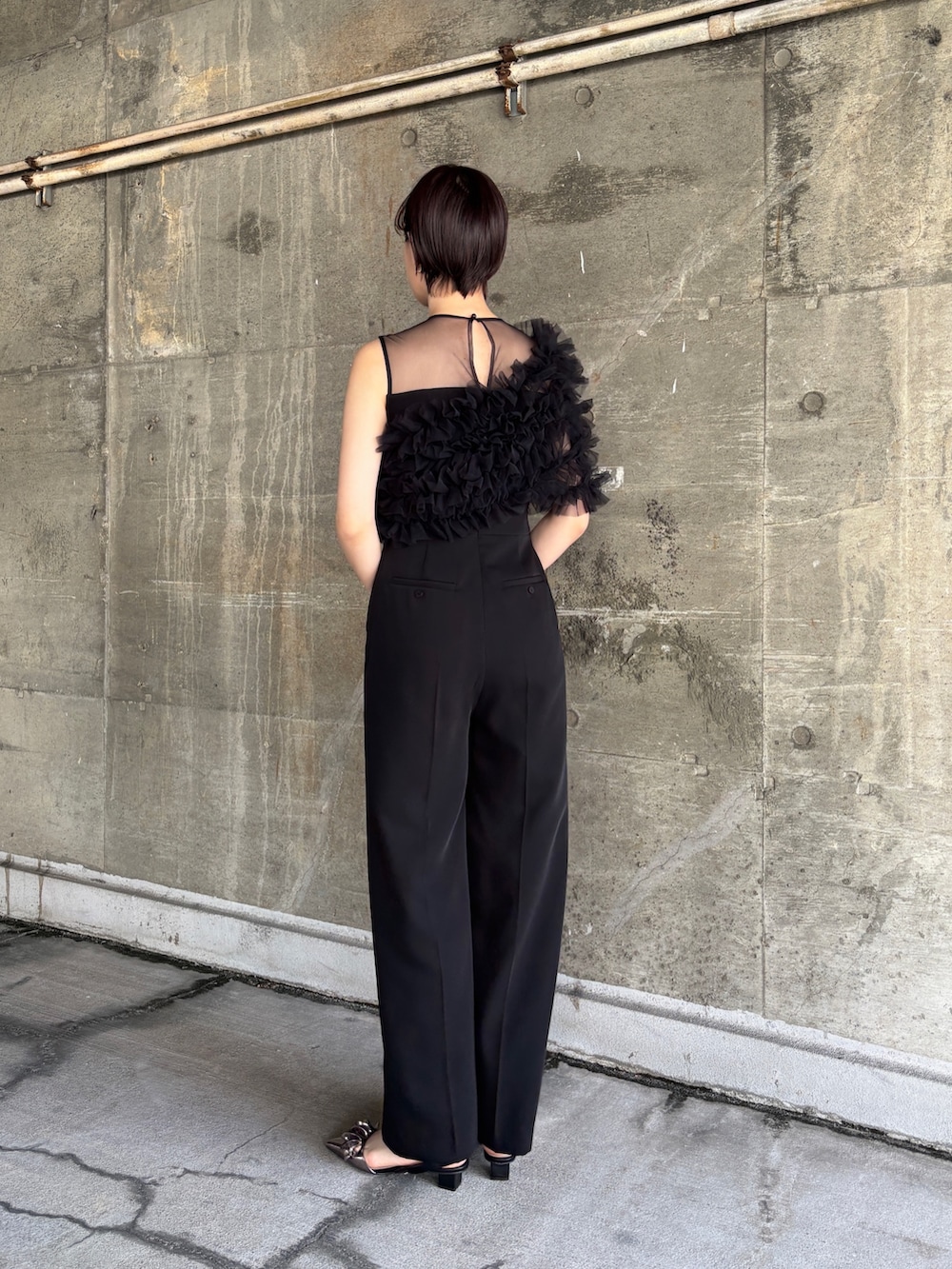 ブラック系のパンツドレス、シルバー系のショルダーバッグ、その他のパンプスを着用したレディースの春コーディネートの2枚目の写真
