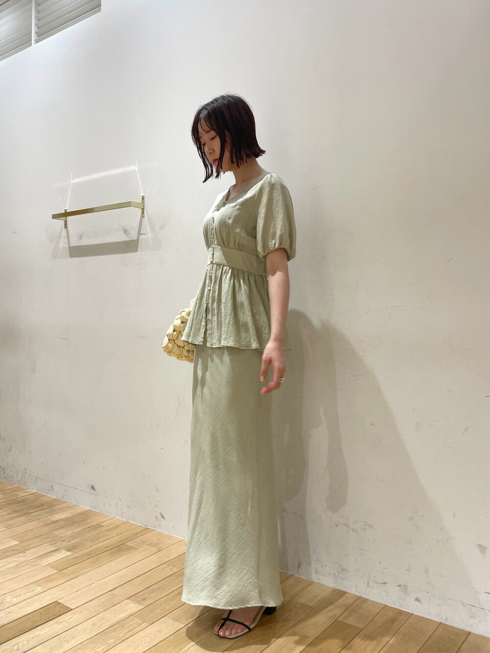 ベージュ系のハンドバッグ、ブラック系のサンダル、グリーン系のスカートを着用したレディースの夏コーディネートの4枚目の写真