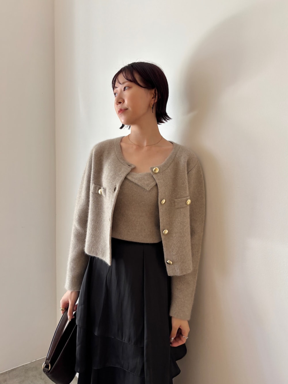 ブラック系のブーツ、ブラウン系のハンドバッグ、ブラック系のスカートを着用したレディースの秋コーディネートの5枚目の写真