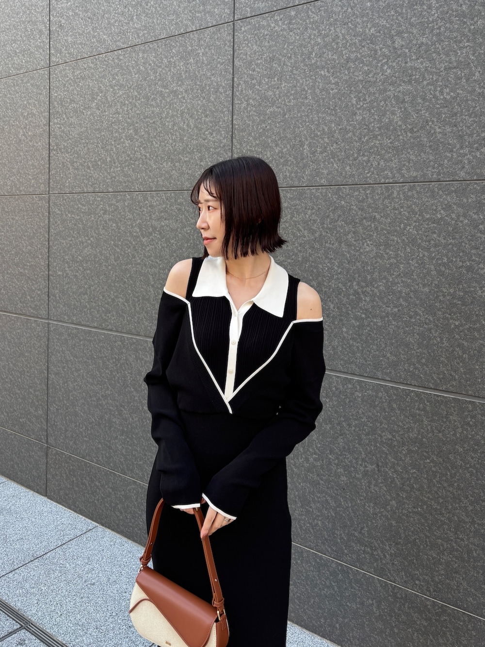 ブラック系のワンピース、ブラウン系のハンドバッグ、ブラック系のパンプスを着用したレディースの春コーディネートの4枚目の写真