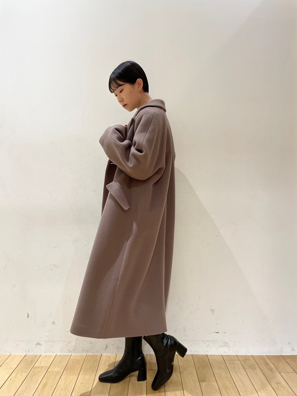 ブラック系のスカート、ホワイト系のニット/セーター、ブラック系のブーツを着用したレディースの冬コーディネートの9枚目の写真