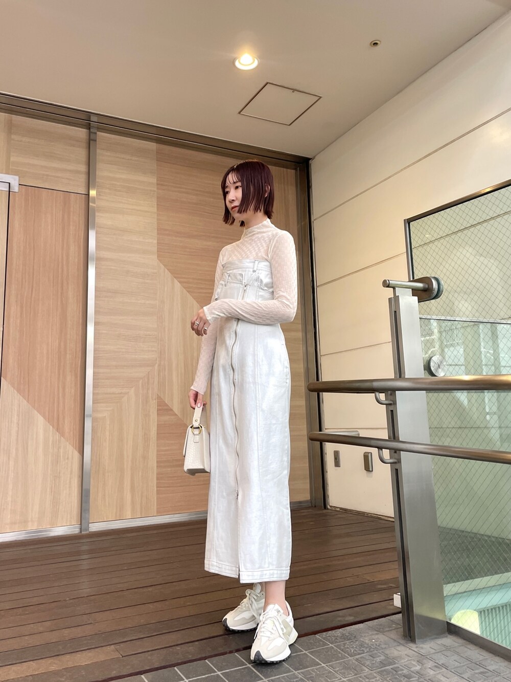 ホワイト系のショルダーバッグ、ホワイト系のワンピース、ブラック系のデニムジャケットを着用したレディースの春コーディネートの2枚目の写真