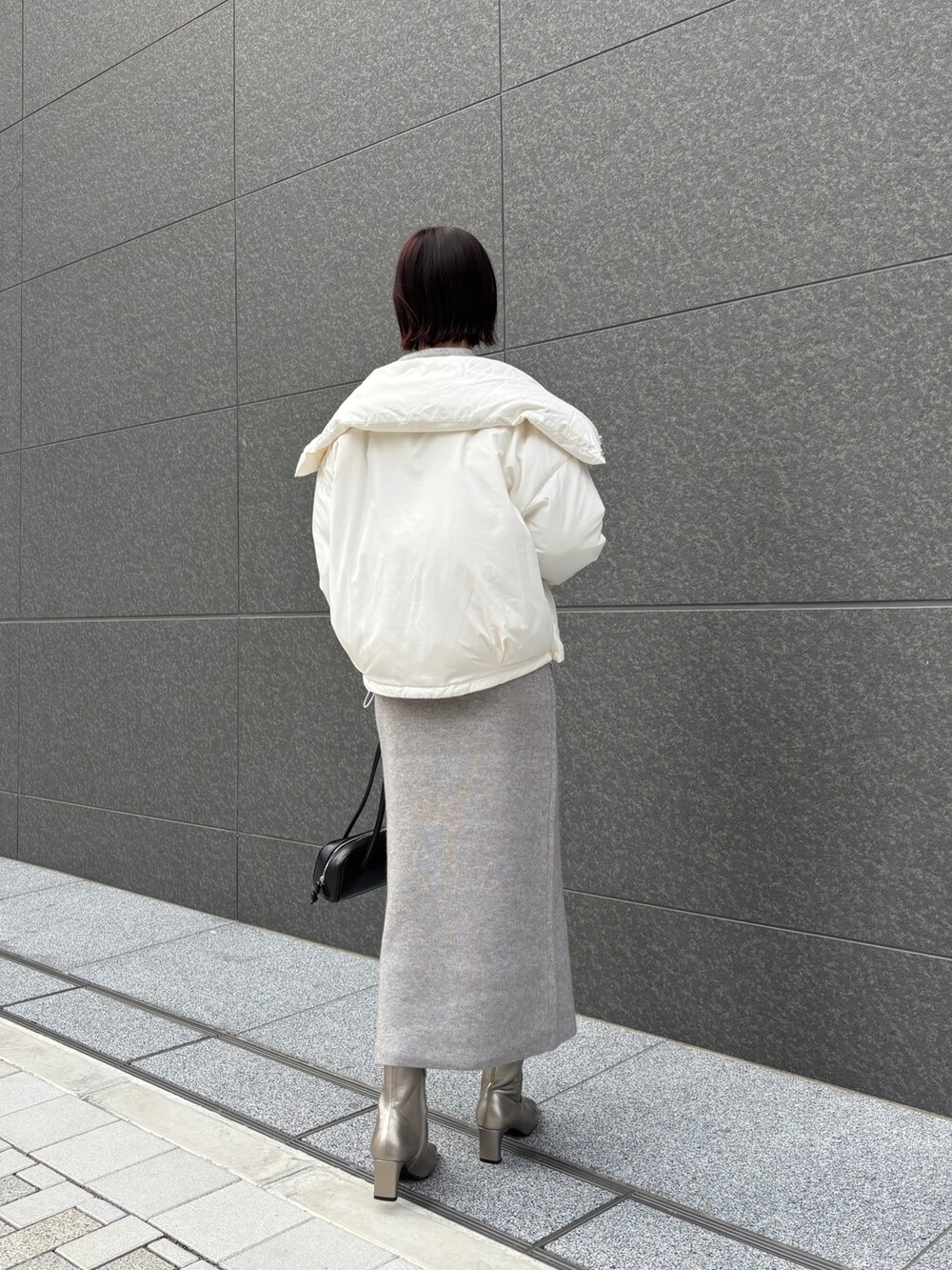 グレー系のワンピース、ホワイト系のダウンジャケット/コート、ブラック系のショルダーバッグを着用したレディースの秋コーディネートの3枚目の写真