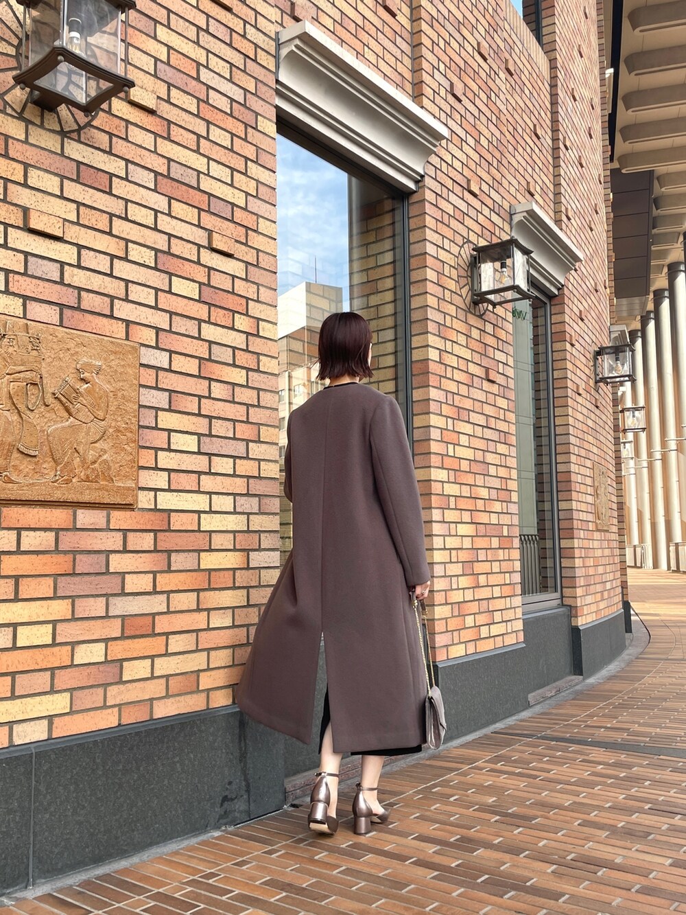 グレー系のノーカラーコート、ブラック系のドレス、シルバー系のハンドバッグを着用したレディースの秋コーディネートの5枚目の写真