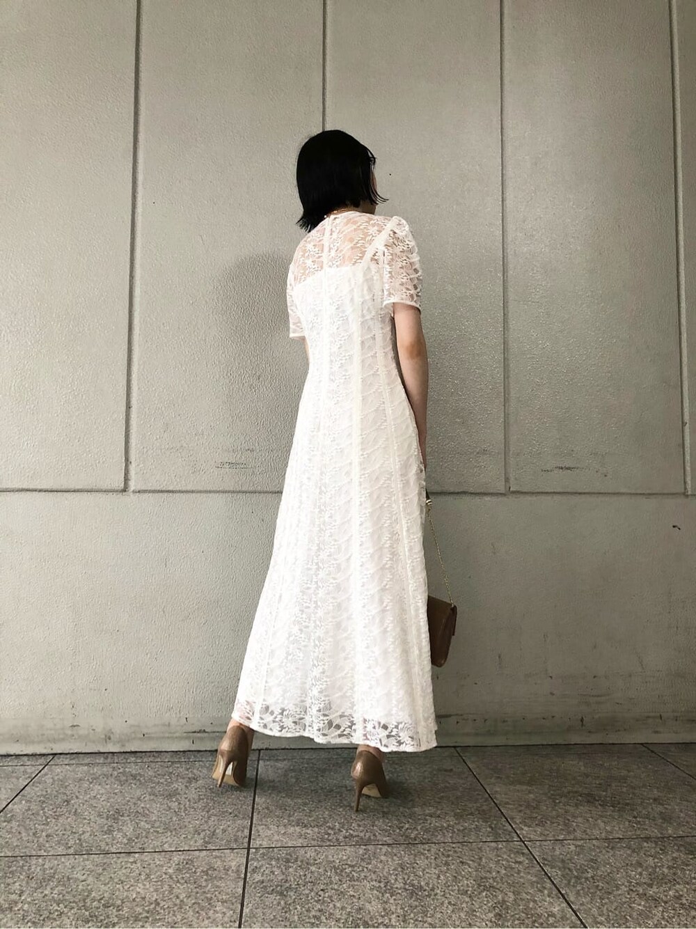 ホワイト系のドレス、ゴールド系のパンプス、ゴールド系のクラッチバッグを着用したレディースの夏コーディネートの6枚目の写真