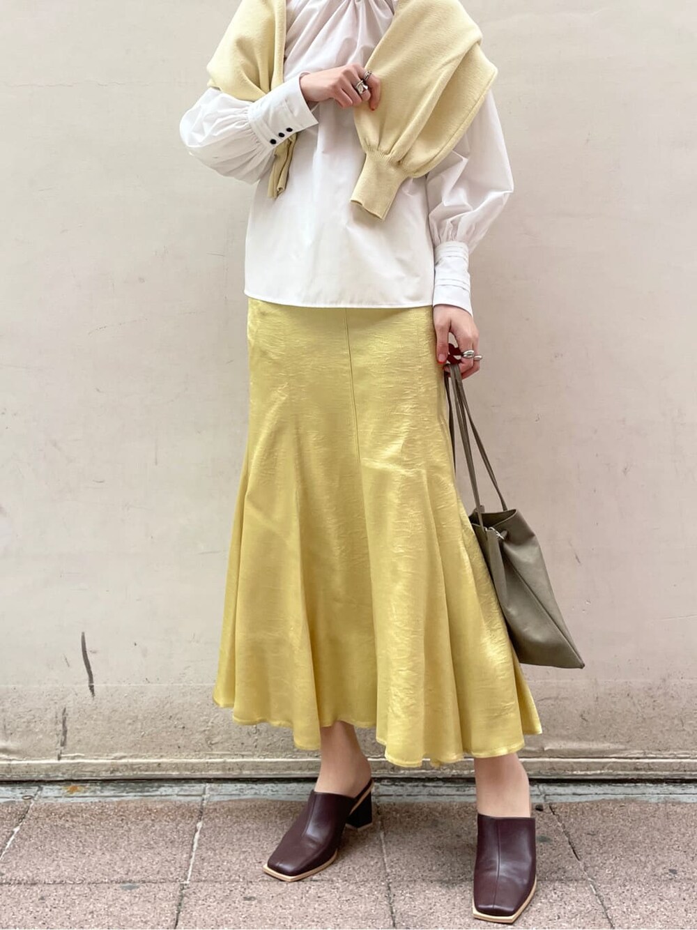 ホワイト系のシャツ/ブラウス、イエロー系のスカート、ベージュ系のハンドバッグを着用したレディースの冬コーディネートの4枚目の写真
