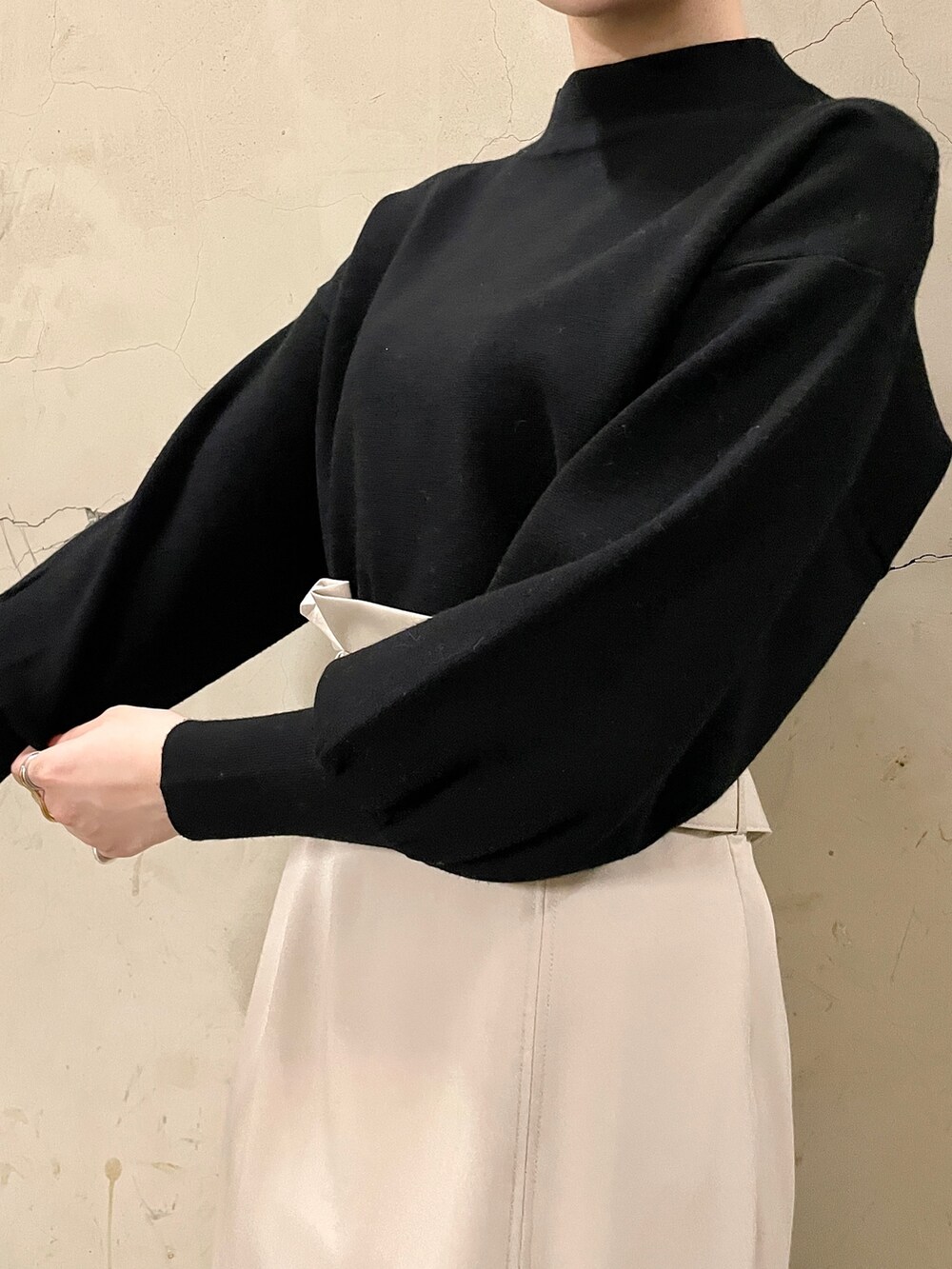 ベージュ系のスカート、ブラック系のニット/セーター、ブラック系のブーツを着用したレディースの秋コーディネートの7枚目の写真