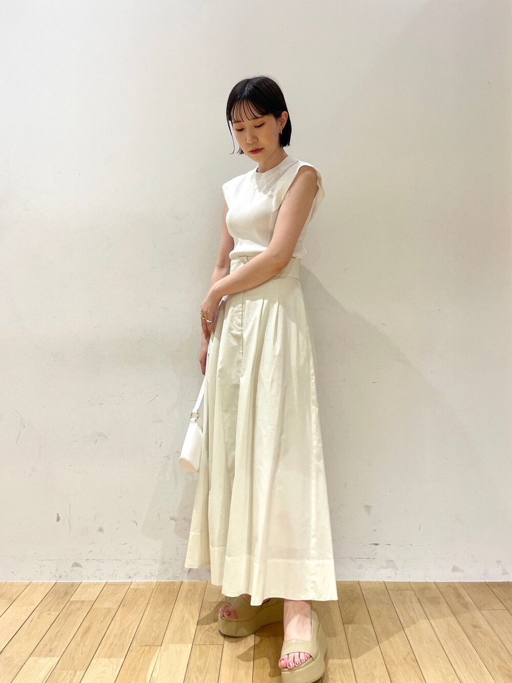 ホワイト系のニット/セーター、ホワイト系のスカート、ホワイト系のハンドバッグを着用したレディースの夏コーディネートの2枚目の写真