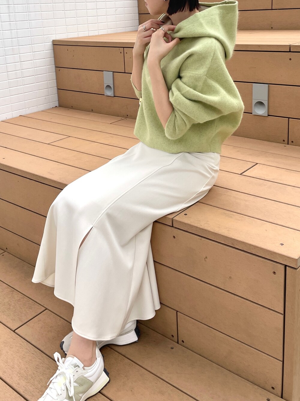 ホワイト系のスカート、グリーン系のパーカー、ホワイト系のブーツを着用したレディースの秋コーディネートの6枚目の写真