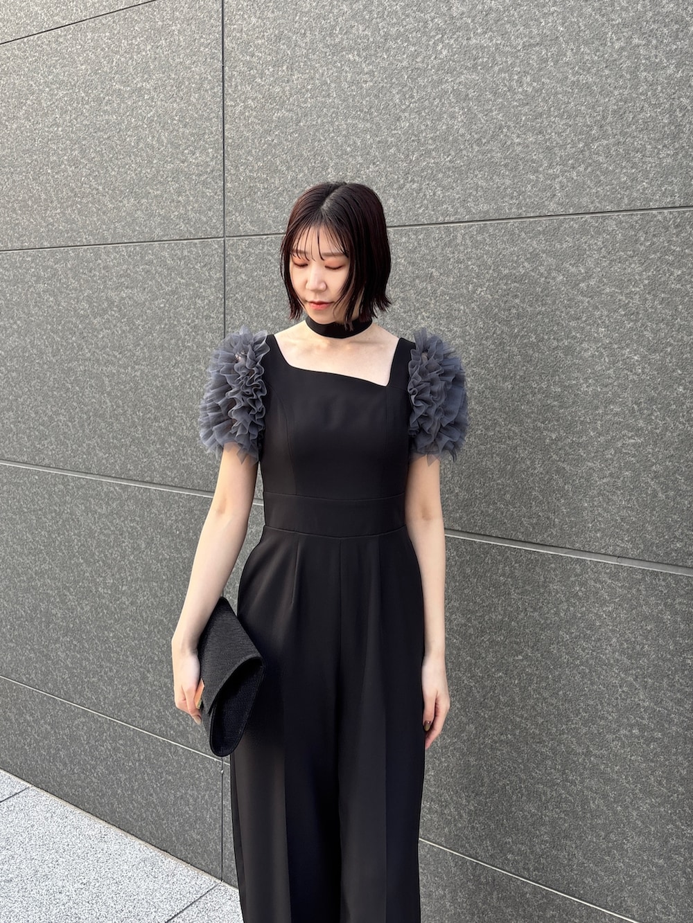 ブラック系のドレス、ブラック系のパンプス、ブラック系のハンドバッグを着用したレディースの冬コーディネートの4枚目の写真