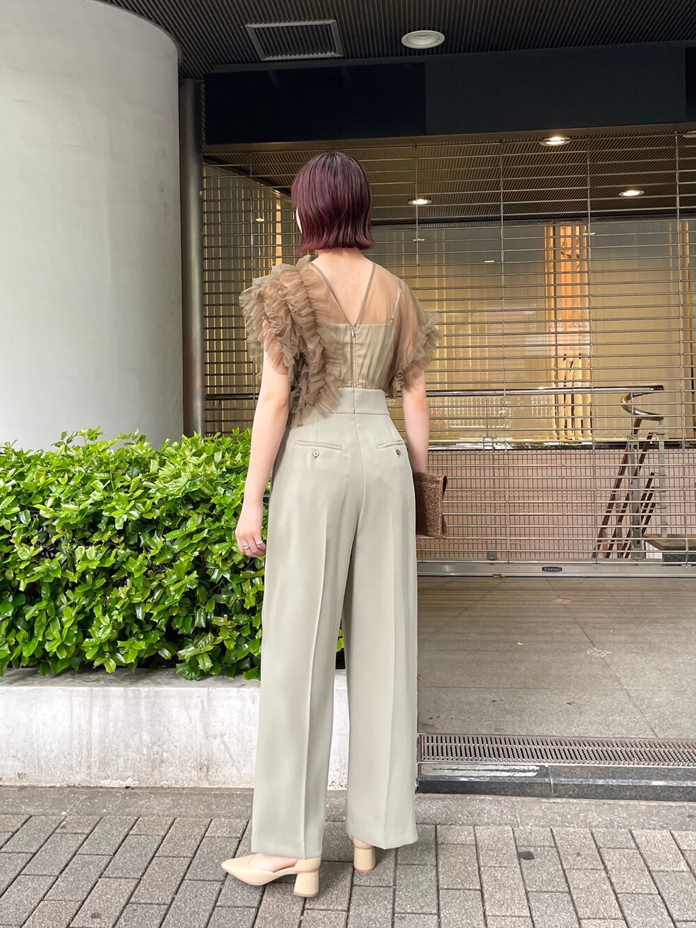 グリーン系のパンツドレス、ベージュ系のパンプスを着用したレディースの春コーディネートの5枚目の写真