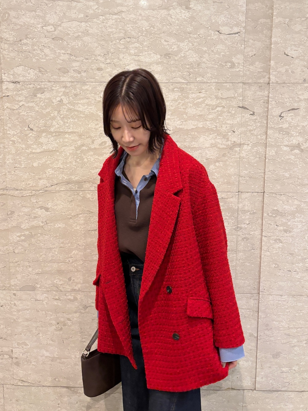 ブルー系のデニムパンツ、ブラウン系のニット/セーター、ブラウン系のハンドバッグを着用したレディースの冬コーディネートの3枚目の写真