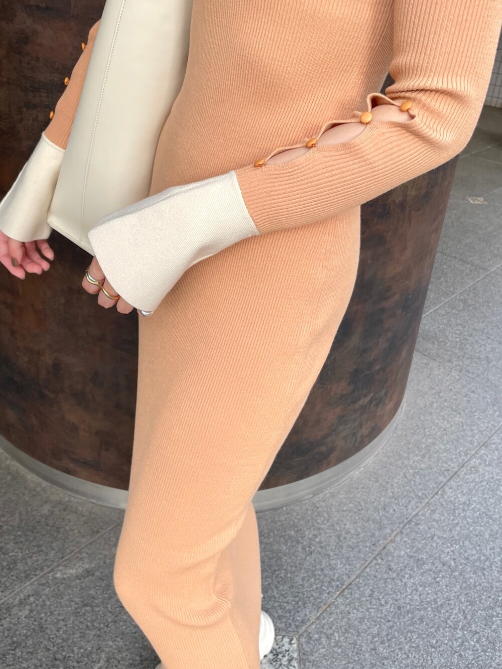 オレンジ系のワンピース、ホワイト系のショルダーバッグ、ブラック系のスニーカーを着用したレディースの冬コーディネートの7枚目の写真