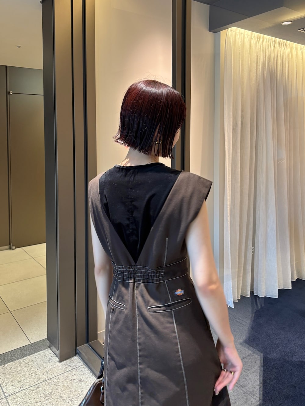 ブラウン系のジャンパースカート、ブラウン系のパンプス、ブラウン系のボストンバッグを着用したレディースの夏コーディネートの6枚目の写真