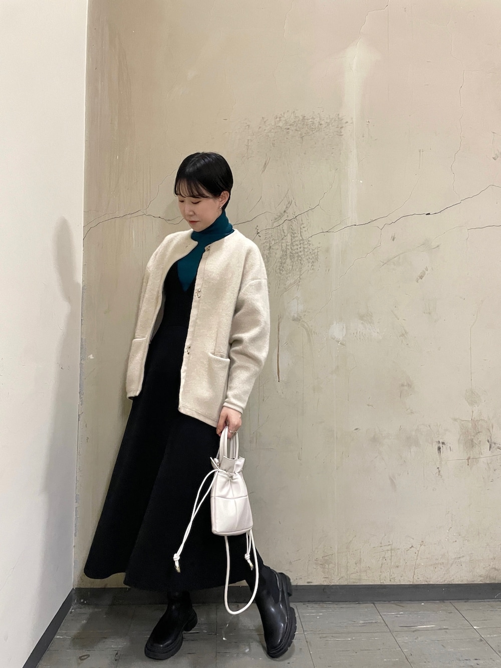 ブラック系のスカート、グリーン系のニット/セーター、ブラック系のブーツを着用したレディースの秋コーディネートの2枚目の写真