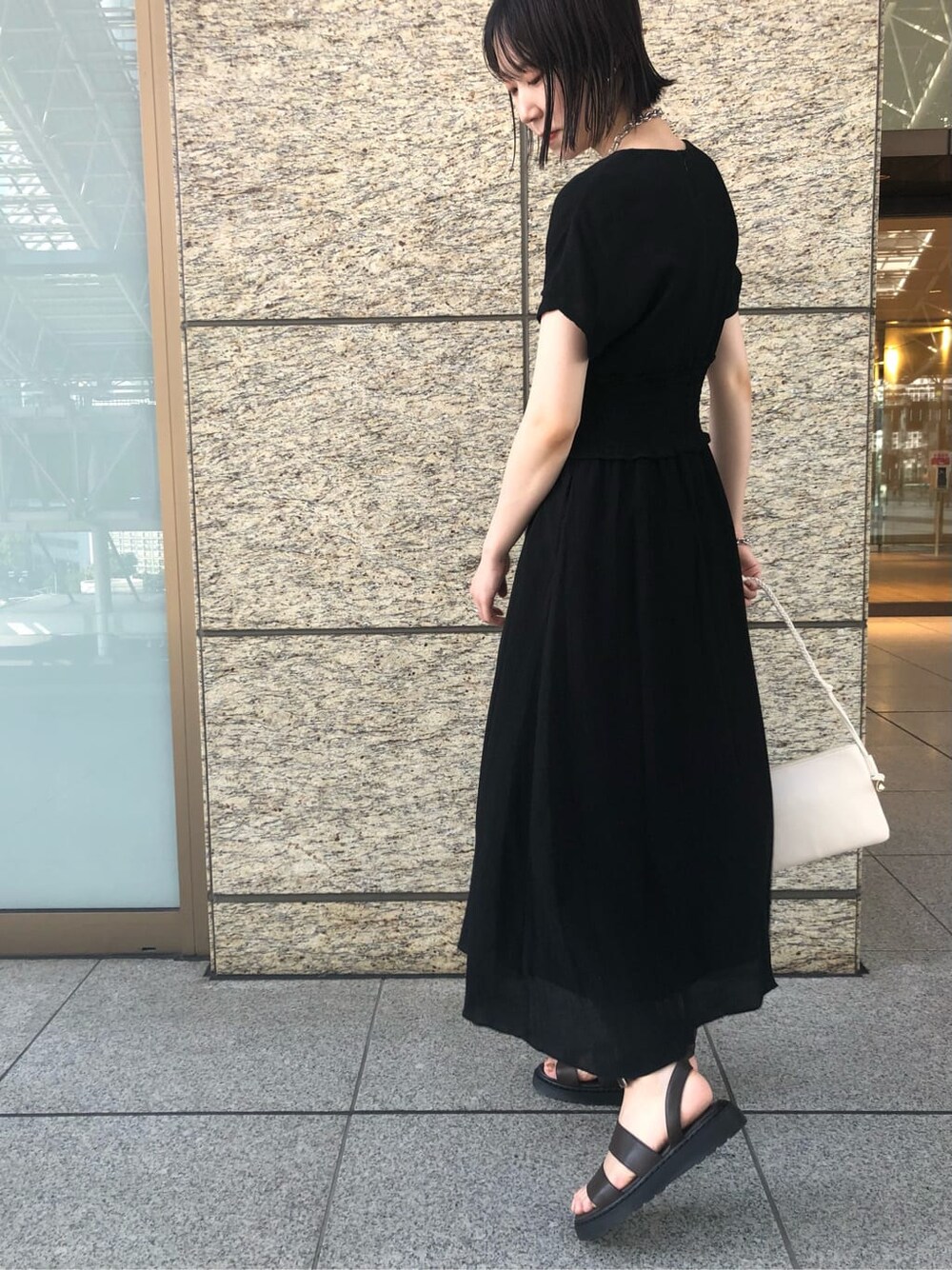 ブラック系のワンピース、ブラウン系のサンダル、シルバー系のブレスレットを着用したレディースの夏コーディネートの7枚目の写真