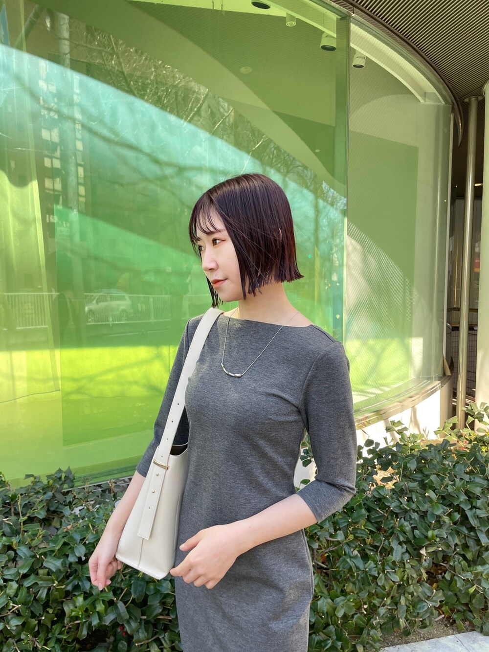 グレー系のワンピース、ホワイト系のショルダーバッグ、ホワイト系のパンプスを着用したレディースの冬コーディネートの5枚目の写真