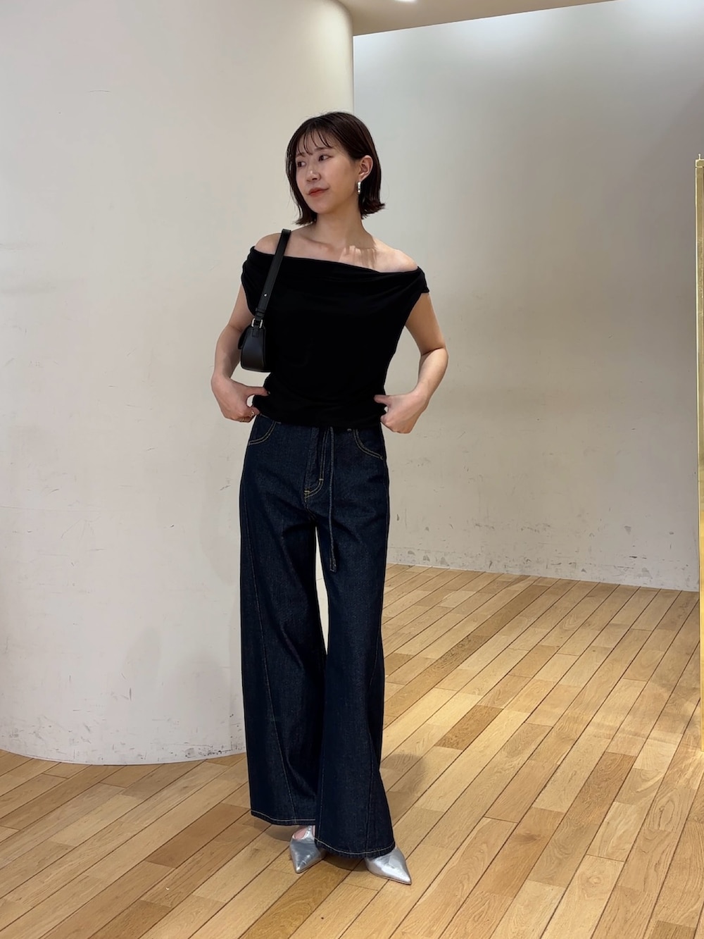 ブルー系のデニムパンツ、ブラック系のハンドバッグ、シルバー系のパンプスを着用したレディースの夏コーディネートの4枚目の写真