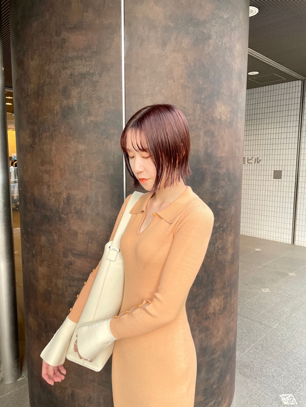 オレンジ系のワンピース、ホワイト系のショルダーバッグ、ブラック系のスニーカーを着用したレディースの冬コーディネートの6枚目の写真