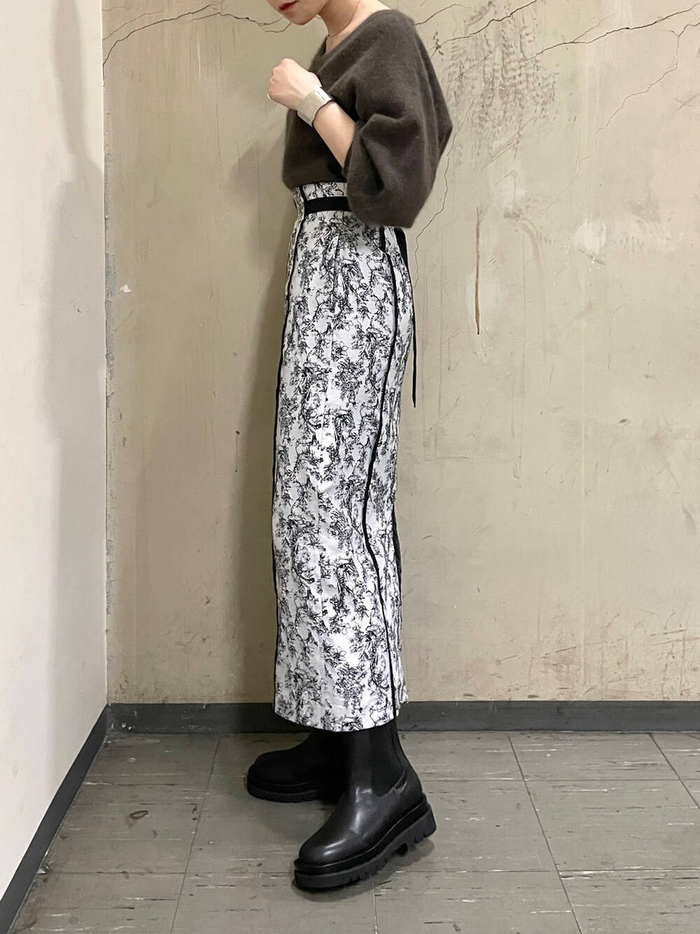 ブラック系のブーツ、ブラウン系のニット/セーター、ブラック系のスカートを着用したレディースの秋コーディネートの4枚目の写真