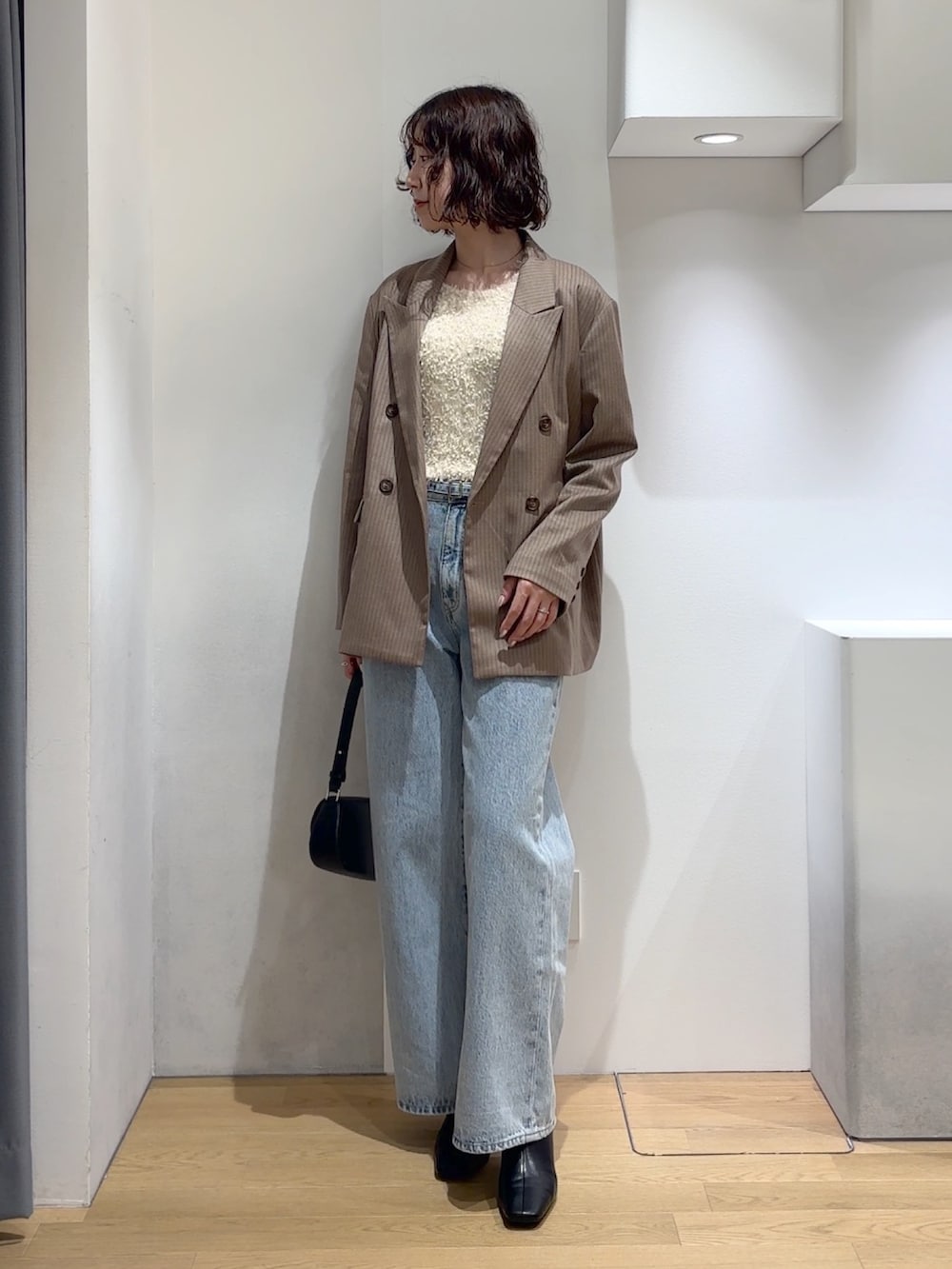 ホワイト系のニット/セーター、ブルー系のデニムパンツ、ブラック系のブーツを着用したレディースの秋コーディネートの4枚目の写真
