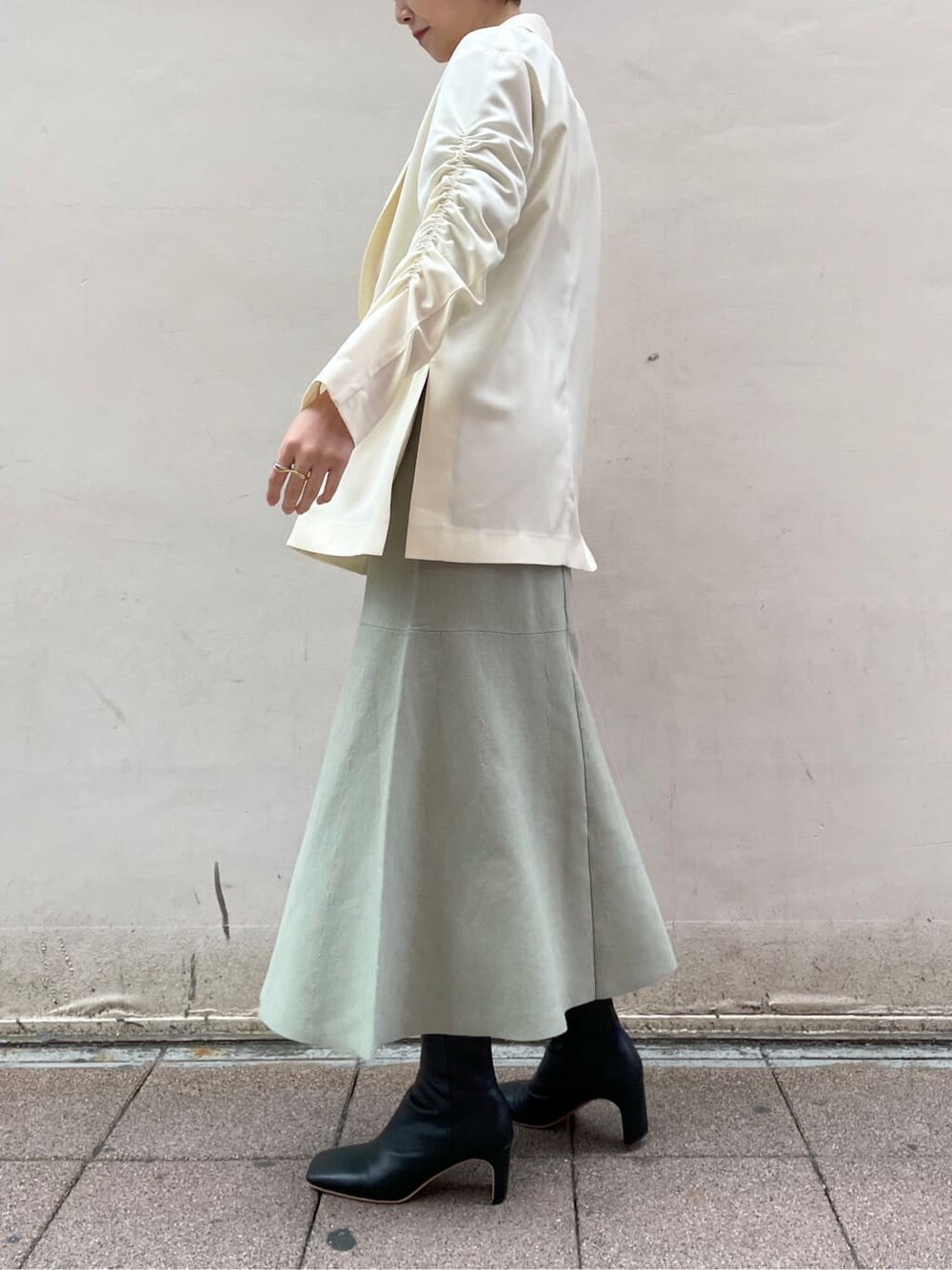 ブラック系のその他シューズ、ホワイト系のテーラードジャケット、グリーン系のワンピースを着用したレディースの冬コーディネートの3枚目の写真