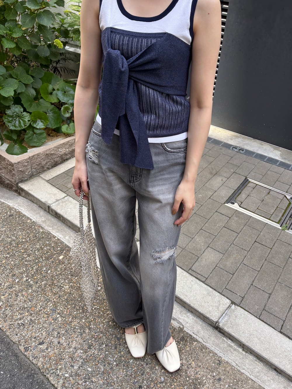 グレー系のデニムパンツ、ホワイト系のニット/セーター、ホワイト系のハンドバッグを着用したレディースの春コーディネートの5枚目の写真