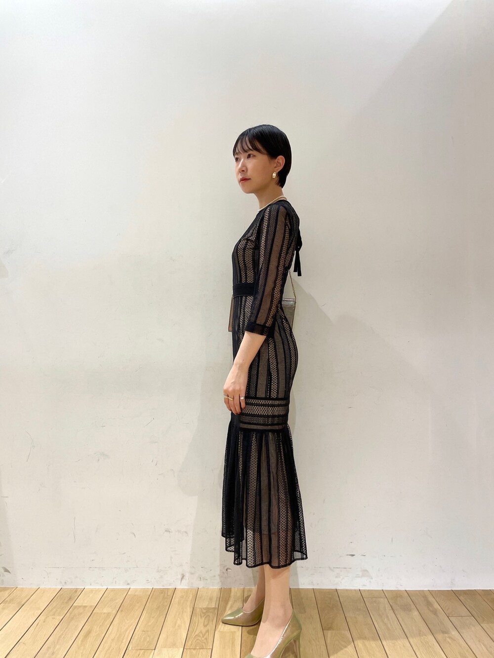 ブラック系のドレス、ゴールド系のハンドバッグ、ゴールド系のパンプスを着用したレディースの冬コーディネートの3枚目の写真