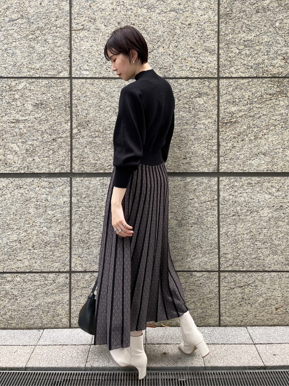 ホワイト系のその他シューズ、ブラック系のワンピース、ベージュ系のその他アウターを着用したレディースの秋コーディネートの6枚目の写真