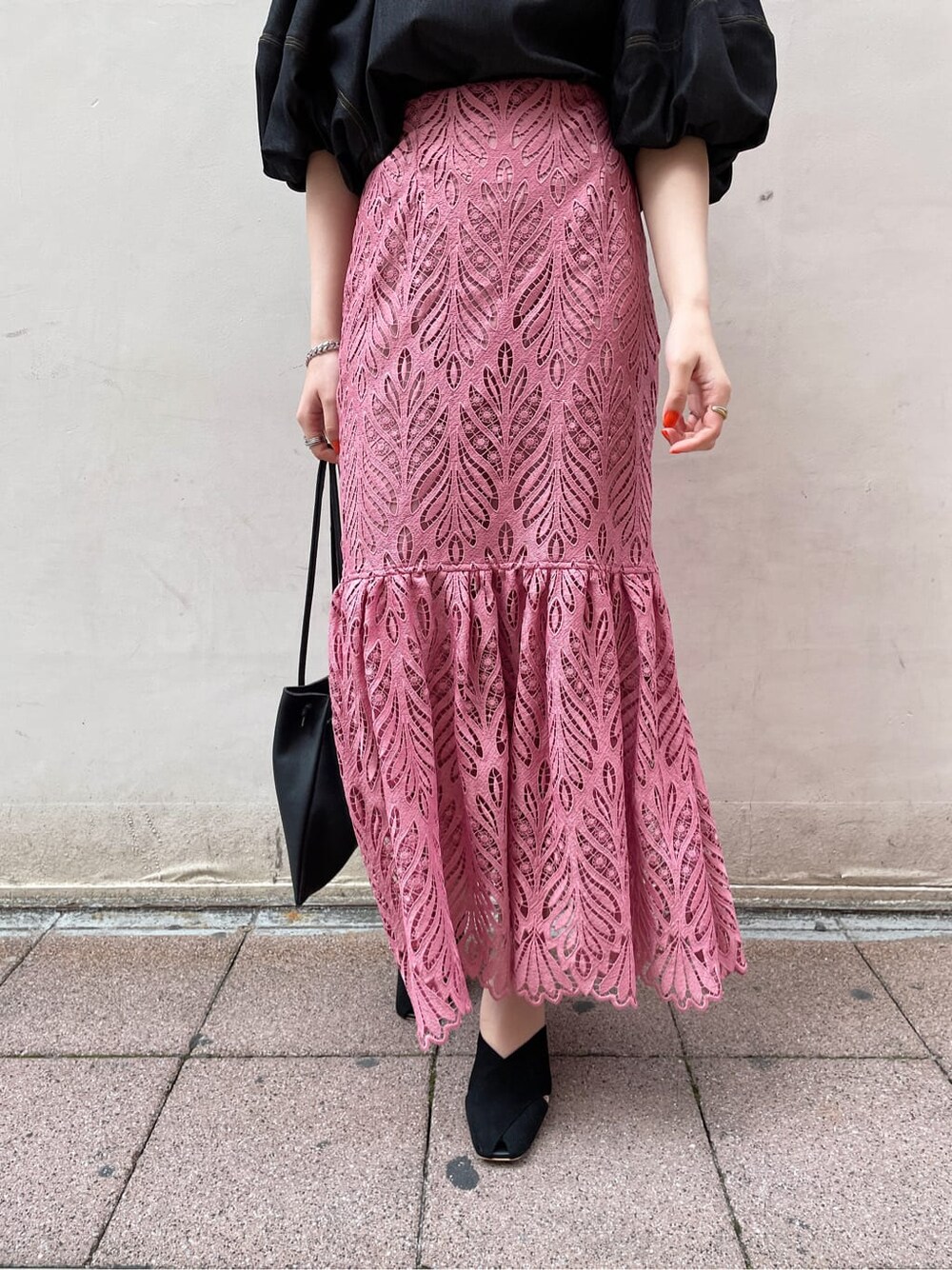 ブラック系のハンドバッグ、ブラック系のサンダル、ピンク系のスカートを着用したレディースの春コーディネートの5枚目の写真