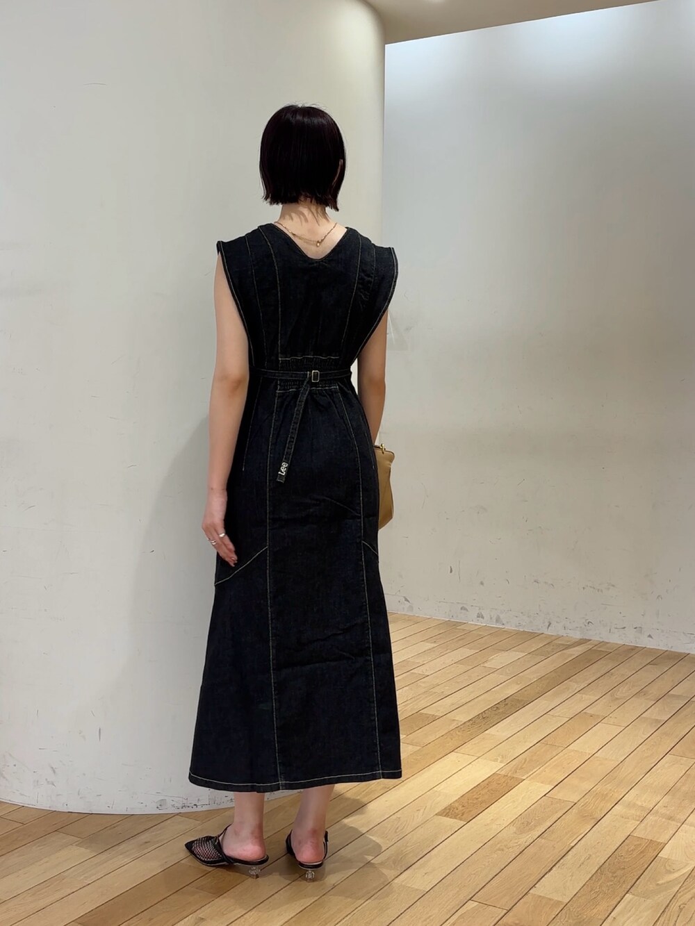 ブラック系のワンピース、ブラック系のサンダル、イエロー系のハンドバッグを着用したレディースの夏コーディネートの5枚目の写真