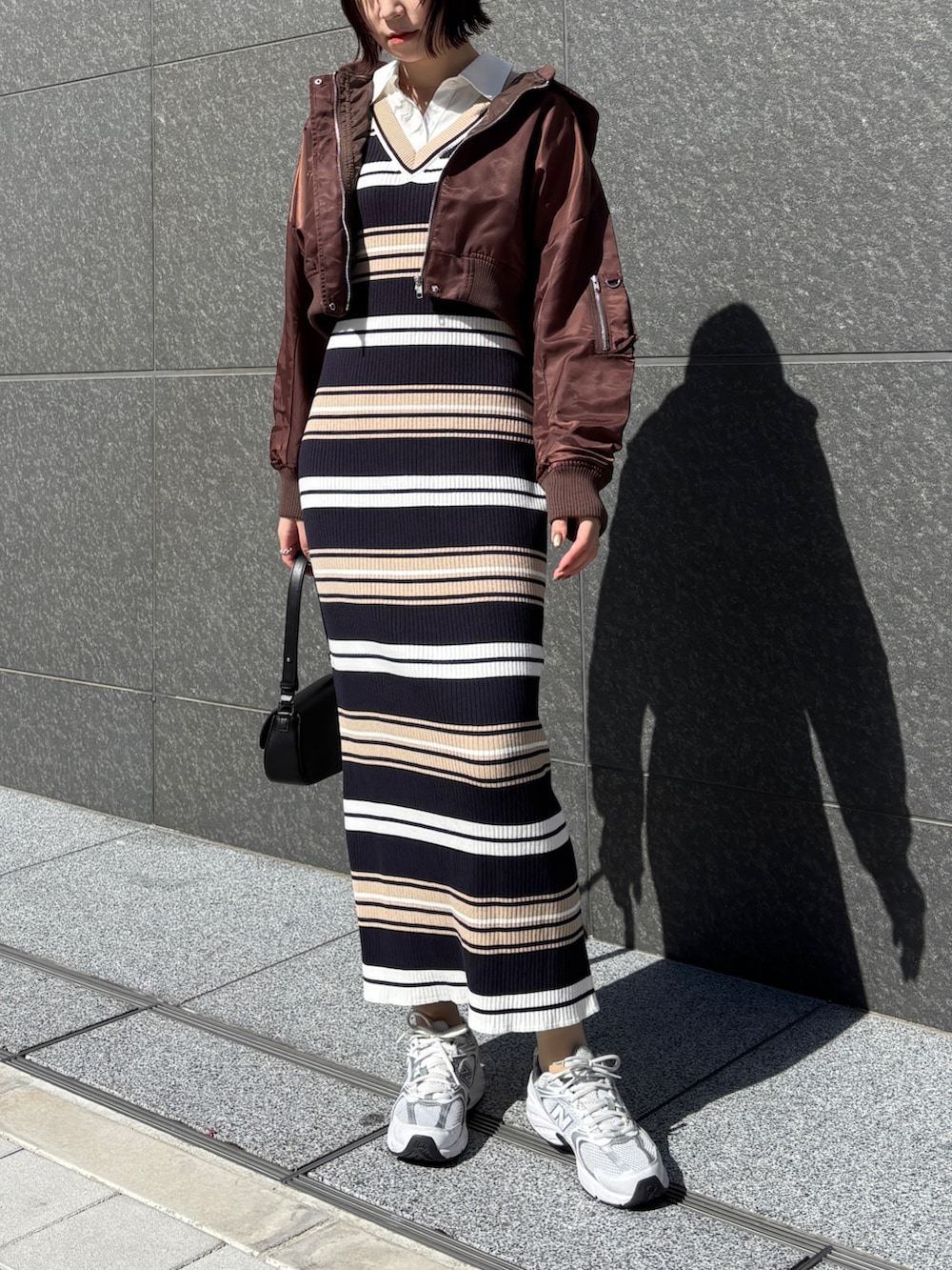 ベージュ系のワンピース、ブラック系のハンドバッグ、ブラウン系のブルゾンを着用したレディースの春コーディネートの2枚目の写真