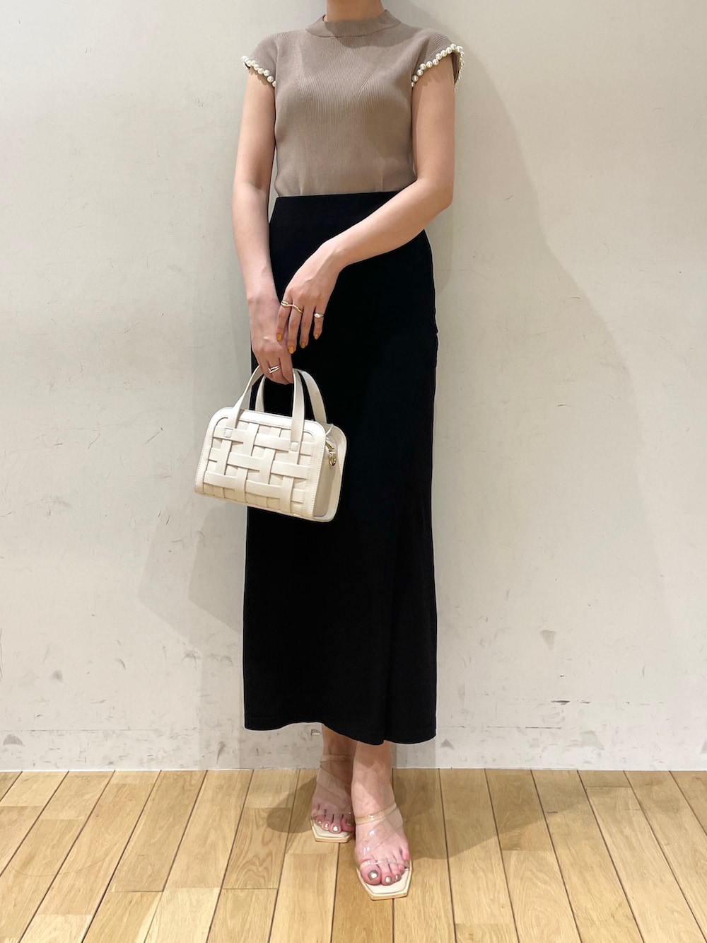 ブラック系のスカート、ベージュ系のニット/セーター、ホワイト系のショルダーバッグを着用したレディースの夏コーディネートの4枚目の写真