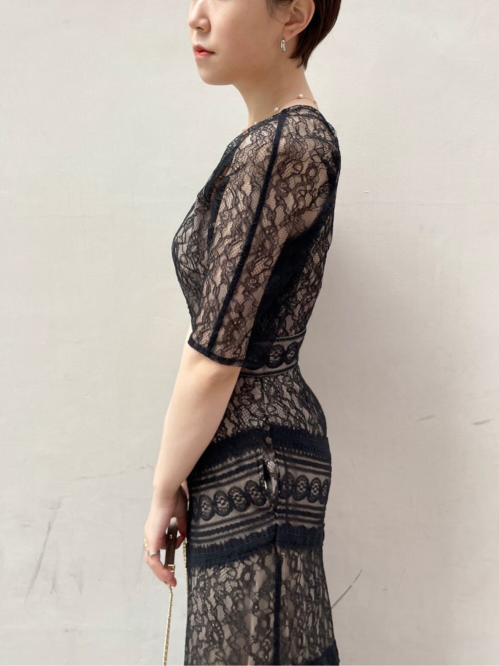 シルバー系のクラッチバッグ、ベージュ系のトレンチコート、シルバー系のパンプスを着用したレディースの冬コーディネートの6枚目の写真