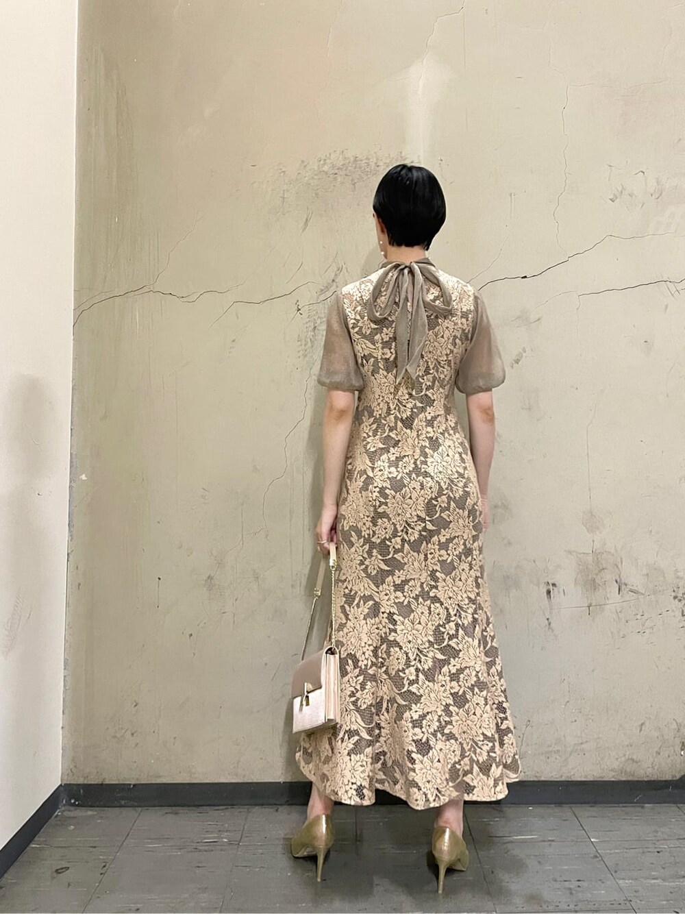 ベージュ系のドレス、ゴールド系のパンプス、ベージュ系のクラッチバッグを着用したレディースの秋コーディネートの3枚目の写真