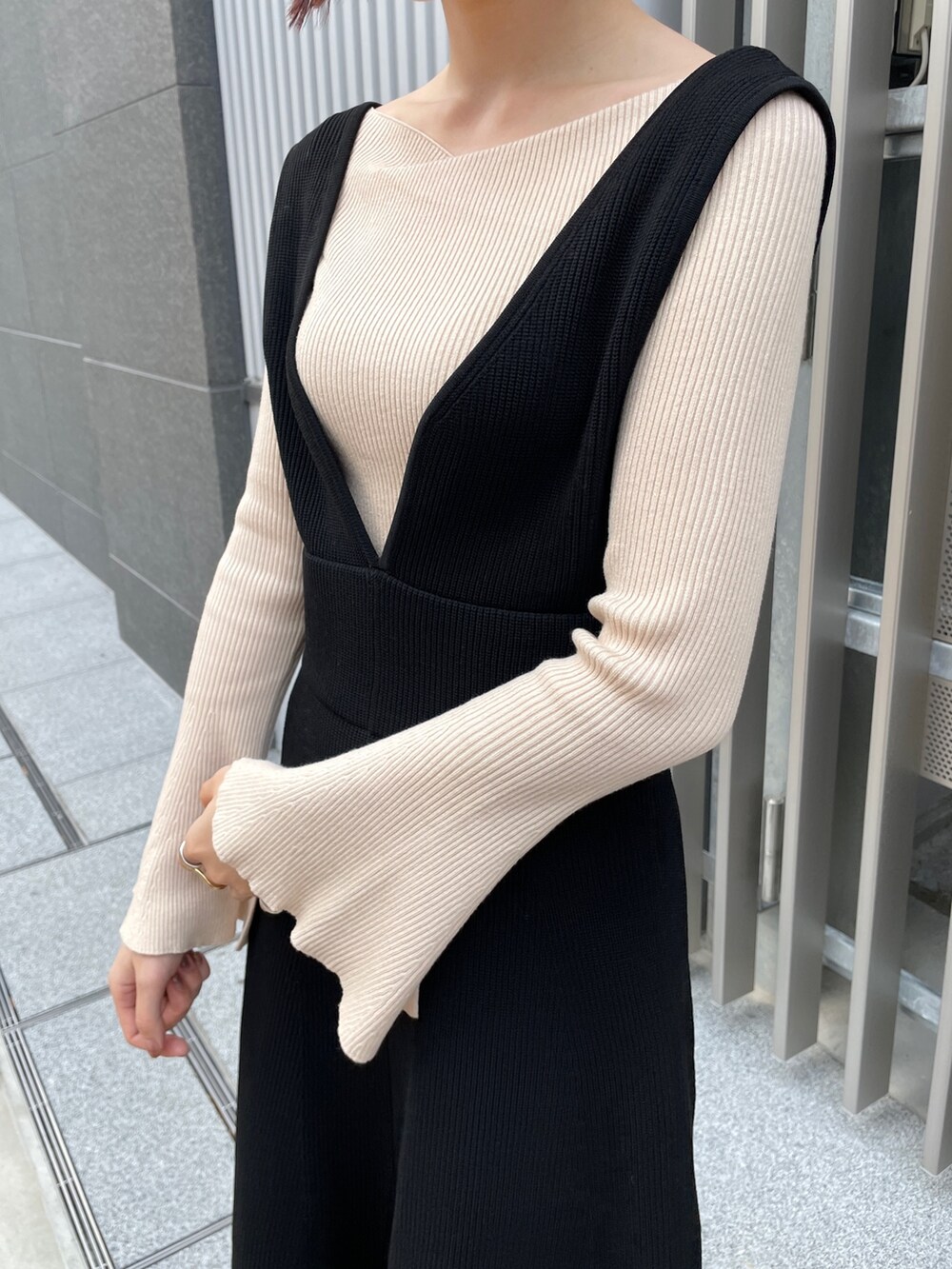 ホワイト系のニット/セーター、ブラック系のジャンパースカート、ブラック系のブーツを着用したレディースの冬コーディネートの5枚目の写真